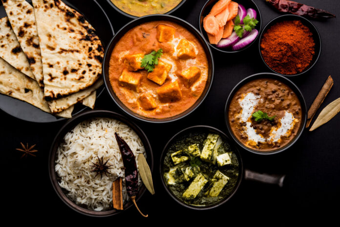Indian Lunch or Dinner main course food in group includes Paneer Butter Masala, Dal Makhani, Palak Paneer, Roti, Rice etc, Selective focus