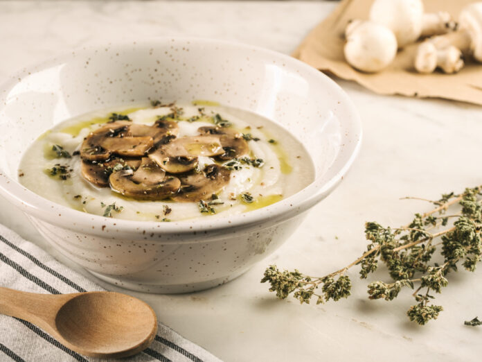 Closeup shot of white soup, creamy and rustic with mushrooms on the table