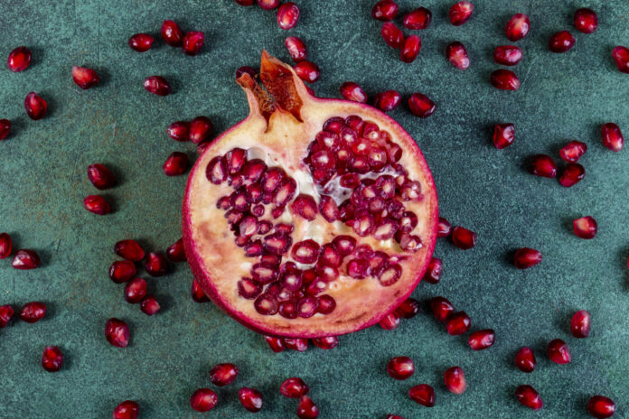 top view chopped half pomegranate with peeled on a green background
