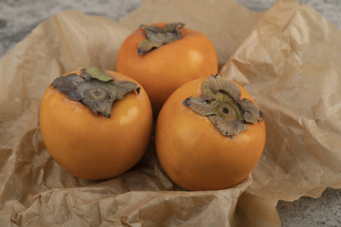 Delicious ripe fuyu fruits placed on paper sheet